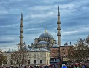 Blue Mosque courtyard with domes, minarets, Iznik tiles, and Bosphorus at dusk.